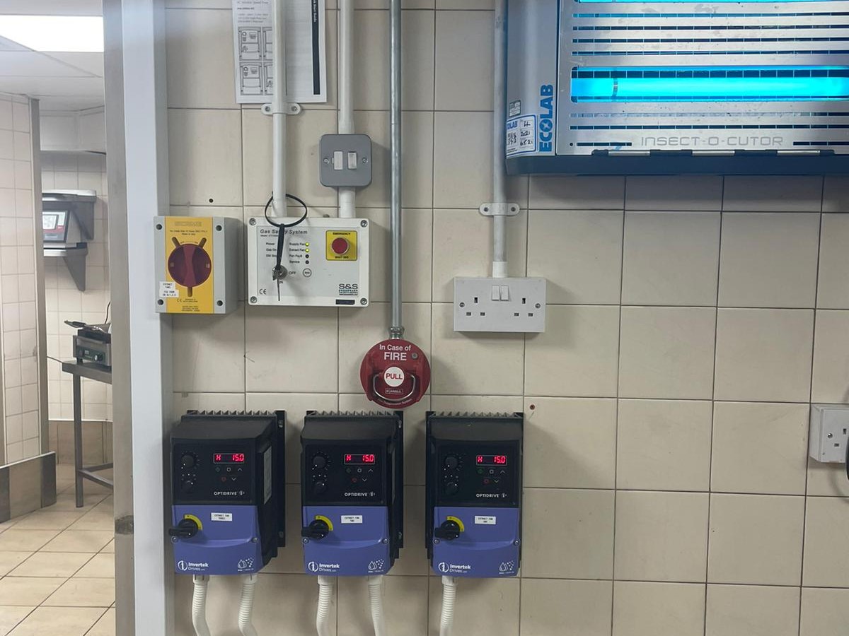 Gauges and a fire alarm on a wall in a commercial kitchen